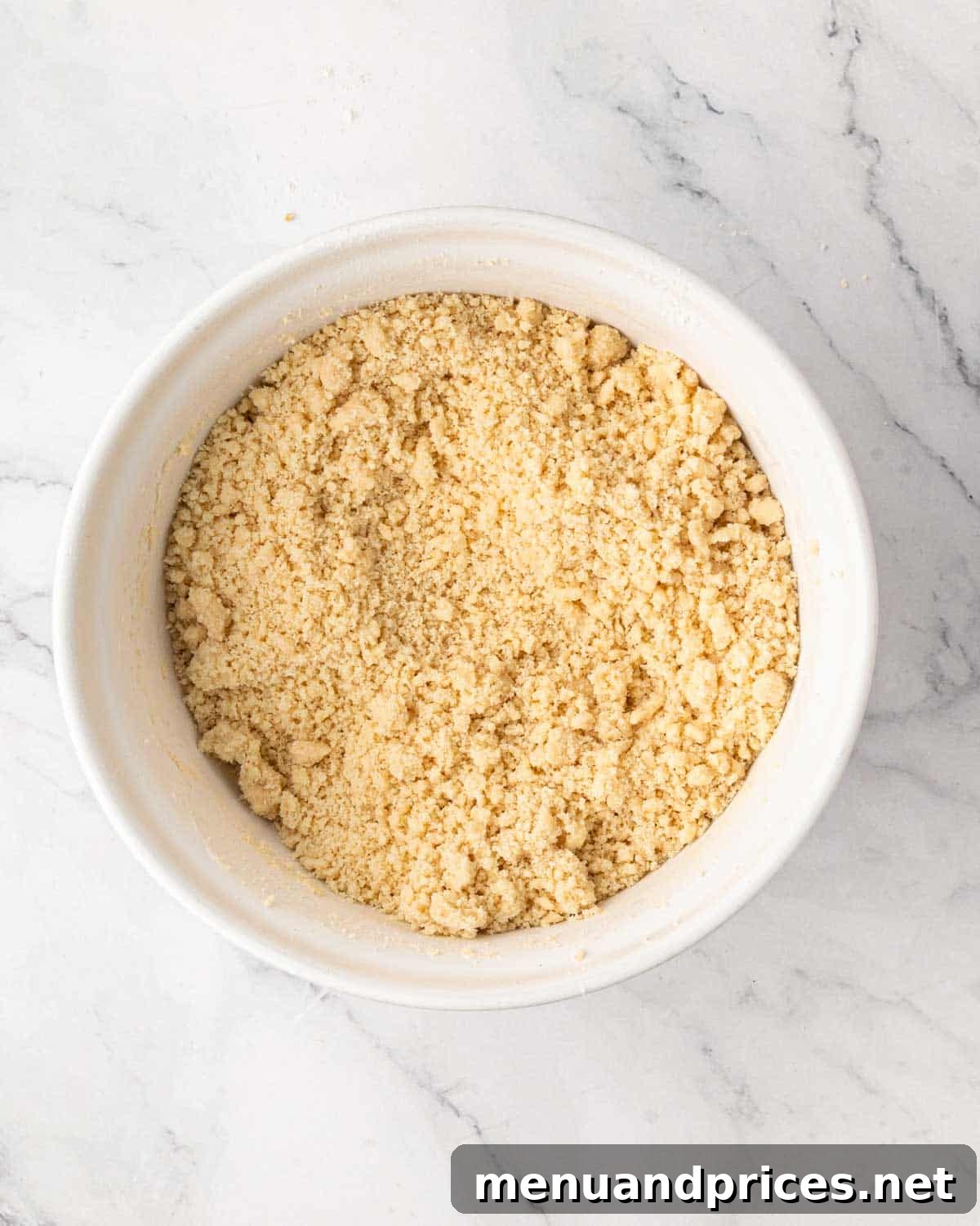 A white bowl with shortbread crust mixture.
