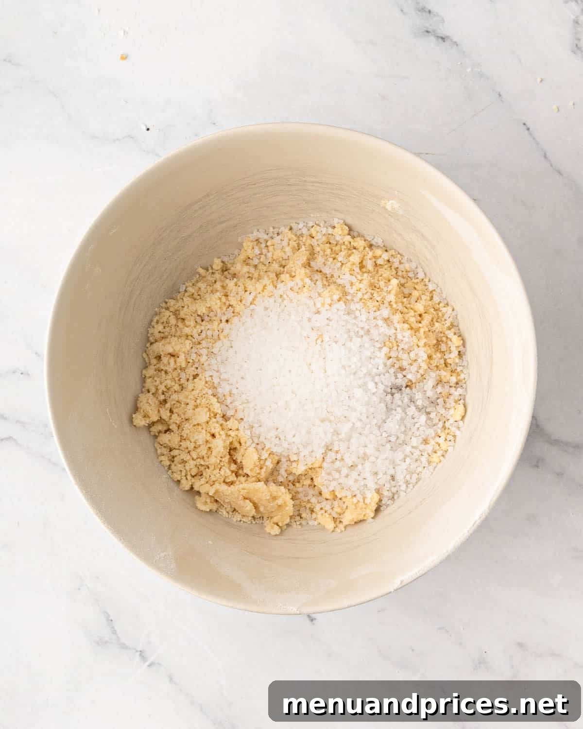 A white bowl with shortbread cookie dough and sugar on top.