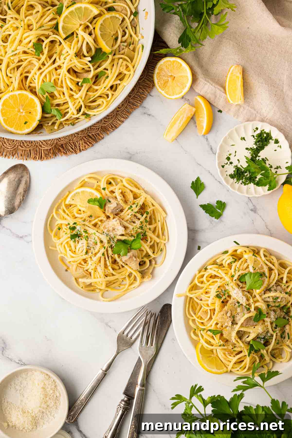 Lemon Artichoke Pasta with Garlic, Parmesan and Herbs 2 Overhead image of lemon artichoke pasta in two white bowls with a bigger serving bowl of pasta in the back.