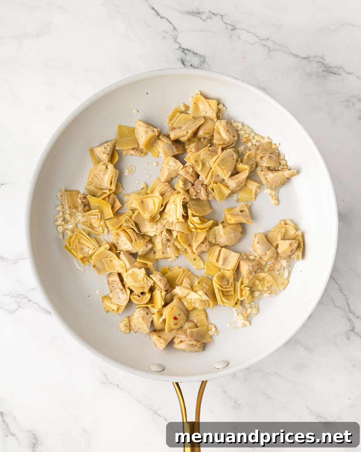 Lemon Artichoke Pasta with Garlic, Parmesan and Herbs 6 A white skillet with artichoke hearts and garlic cooking.