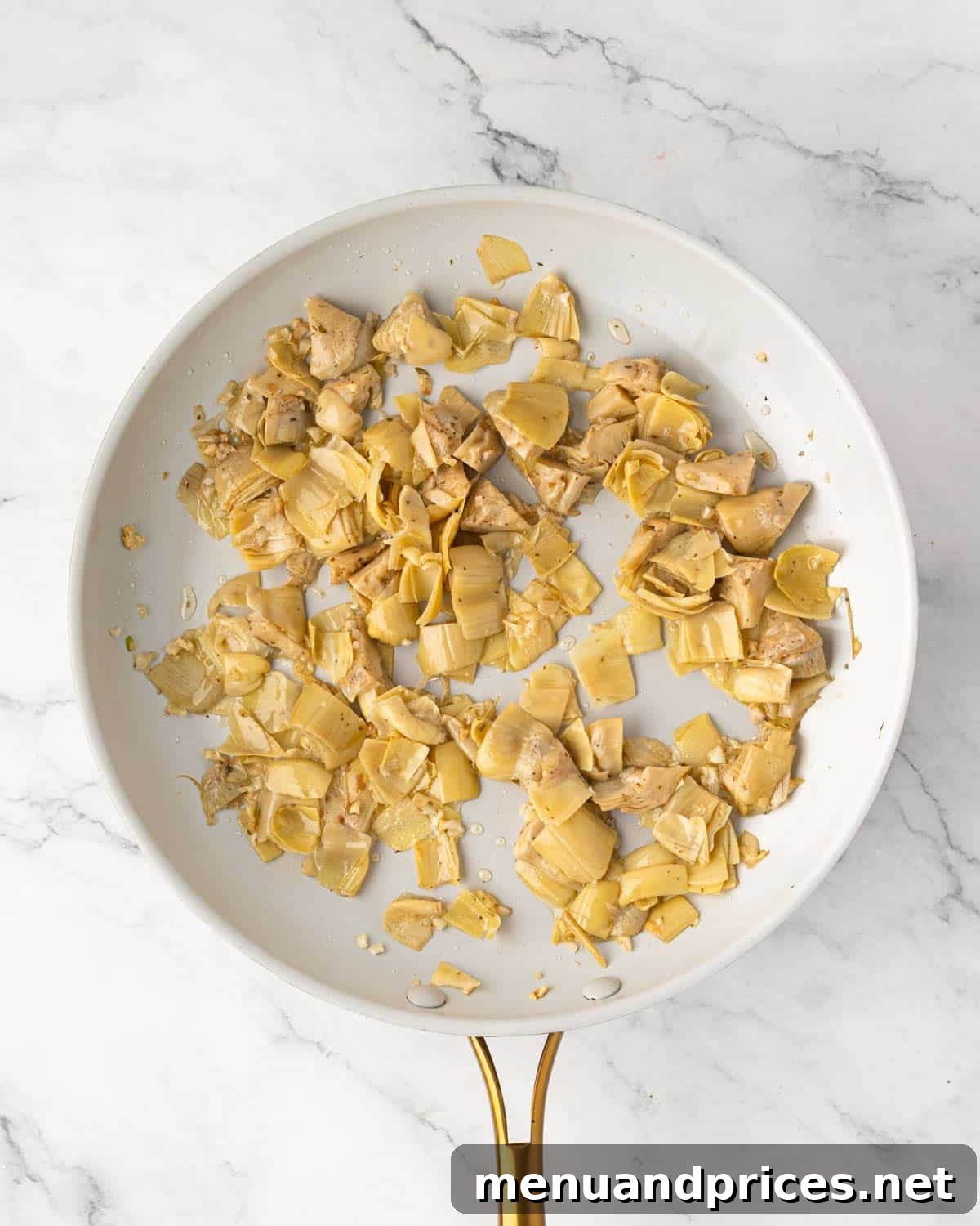 Lemon Artichoke Pasta with Garlic, Parmesan and Herbs 7 Cooked garlic and artichoke hearts in a white skillet.