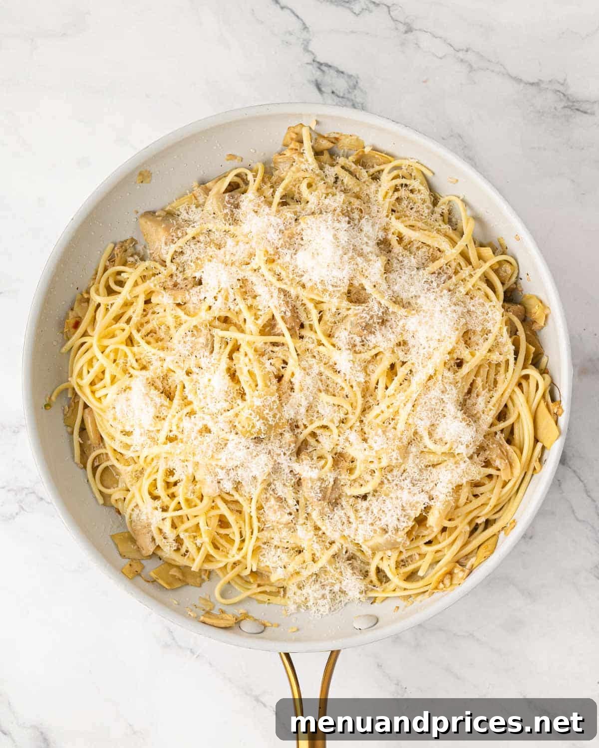 Lemon Artichoke Pasta with Garlic, Parmesan and Herbs 8 A white skillet with pasta and artichokes and grated parmesan cheese on top.
