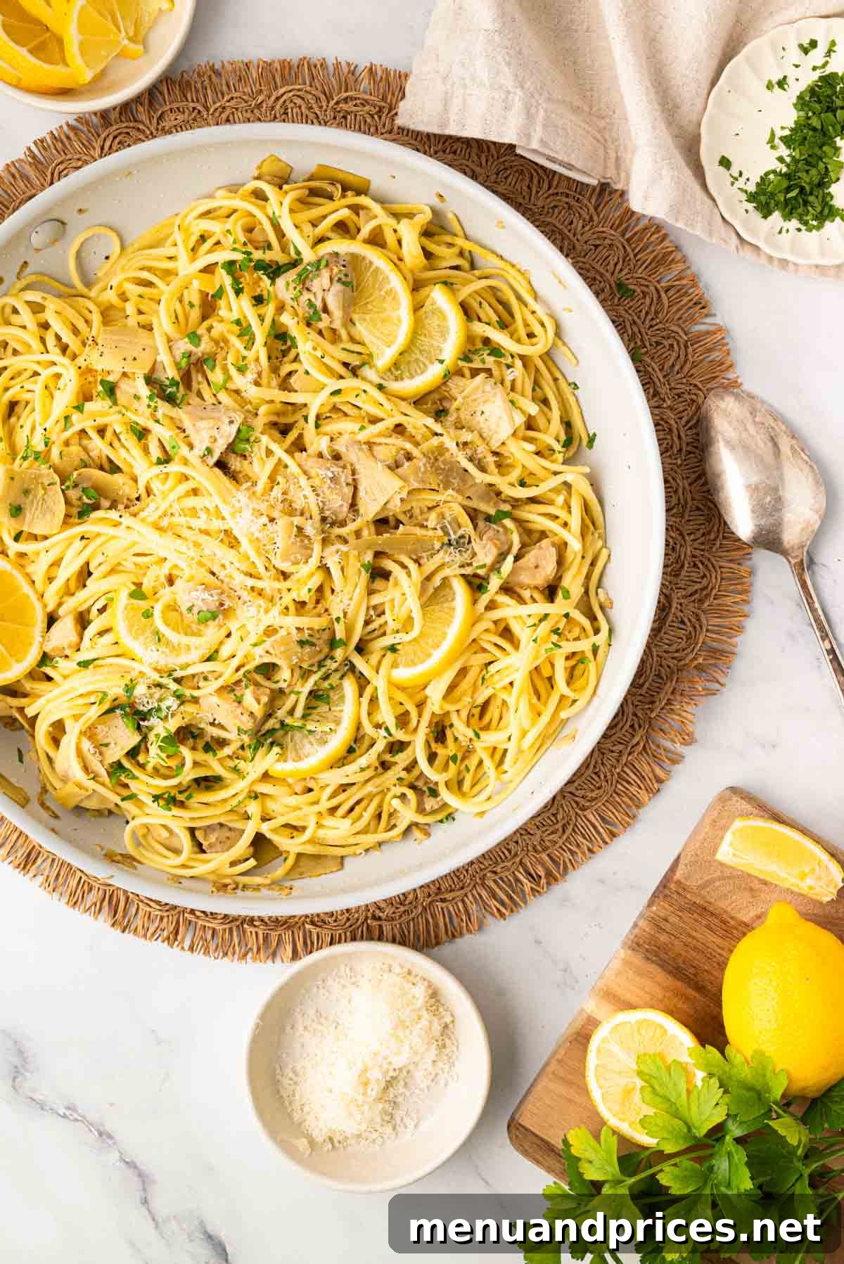 Lemon Artichoke Pasta with Garlic, Parmesan and Herbs 10 A white skillet with artichoke pasta on a wicker placemat with a spoon and grated parmesan cheese on the side.